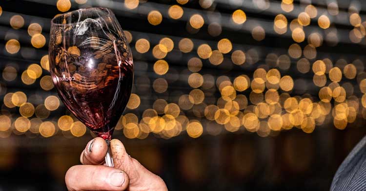 hand swirls red wine in glass