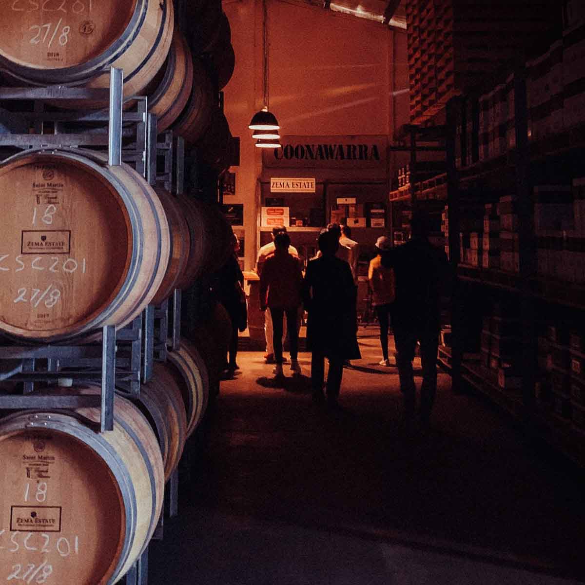 people walk down dimly lit winery museum area