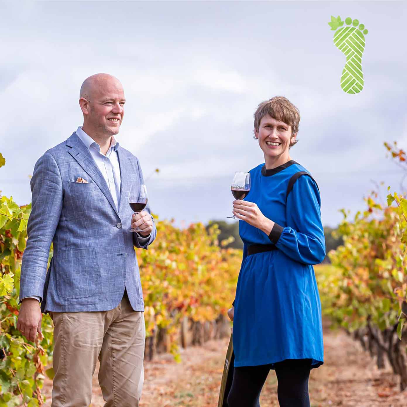 man and woman walk through winery in winter with glass of red wine