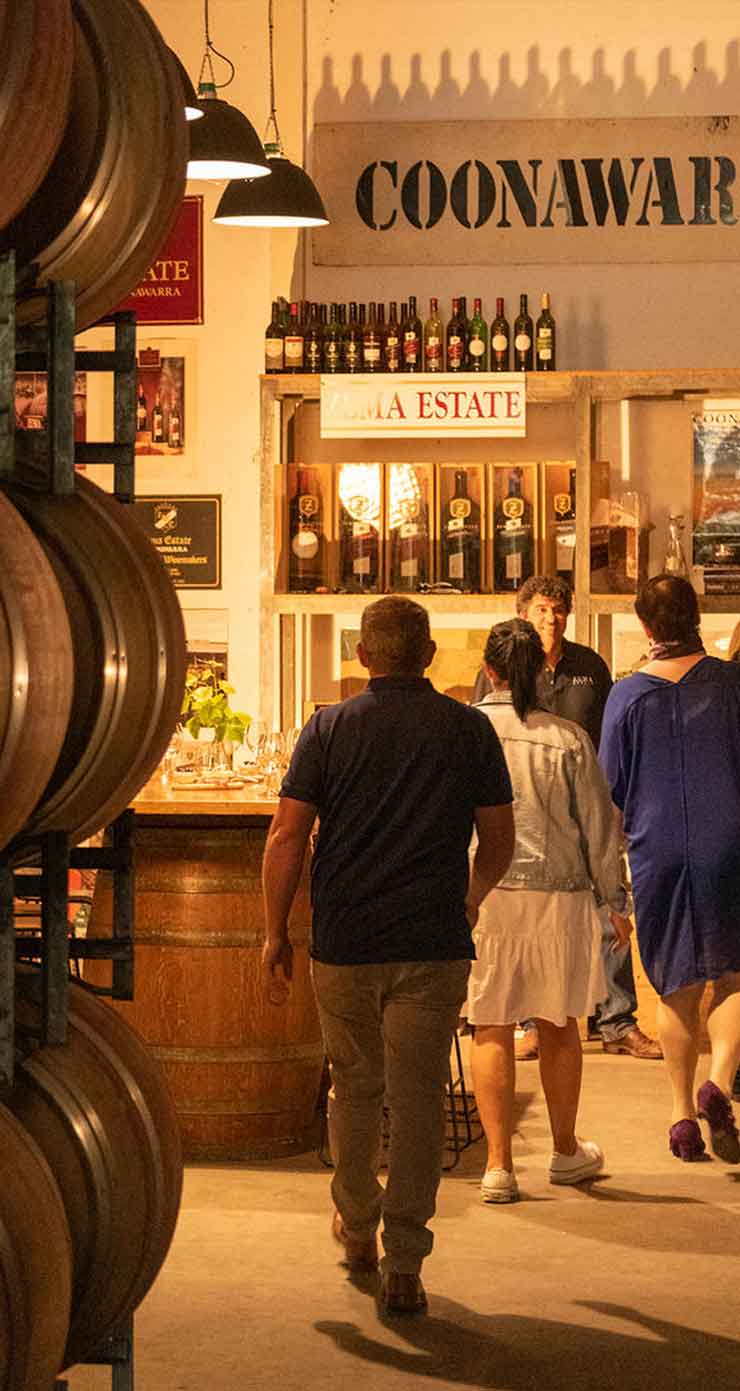 people walk down a dimly lit winery cellar for tasting