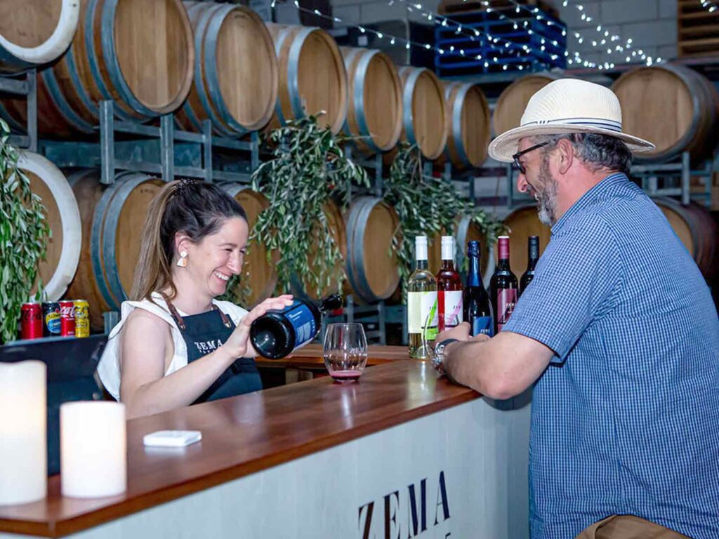 Lady pours wine for man at zema estate event