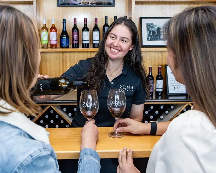 woman pours wine at winery tasting in cellar door