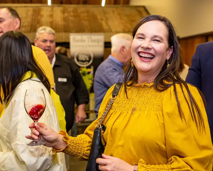 Lady in yellow smiles and drinks a coonawarra cabernet